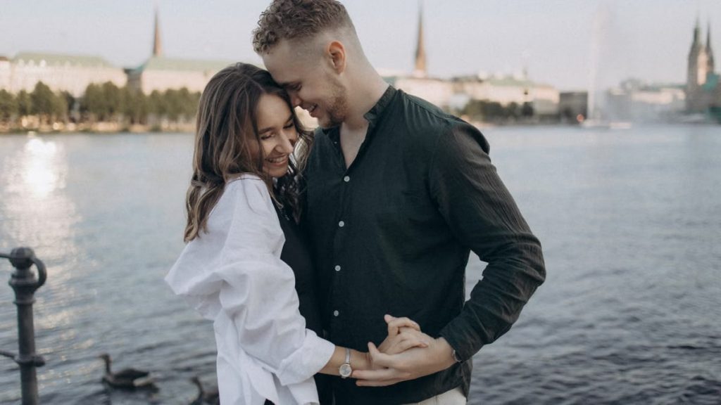 Happy couple embracing by the Alster Lake in Hamburg, Germany during a beautiful summer evening.