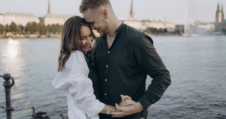 Happy couple embracing by the Alster Lake in Hamburg, Germany during a beautiful summer evening.